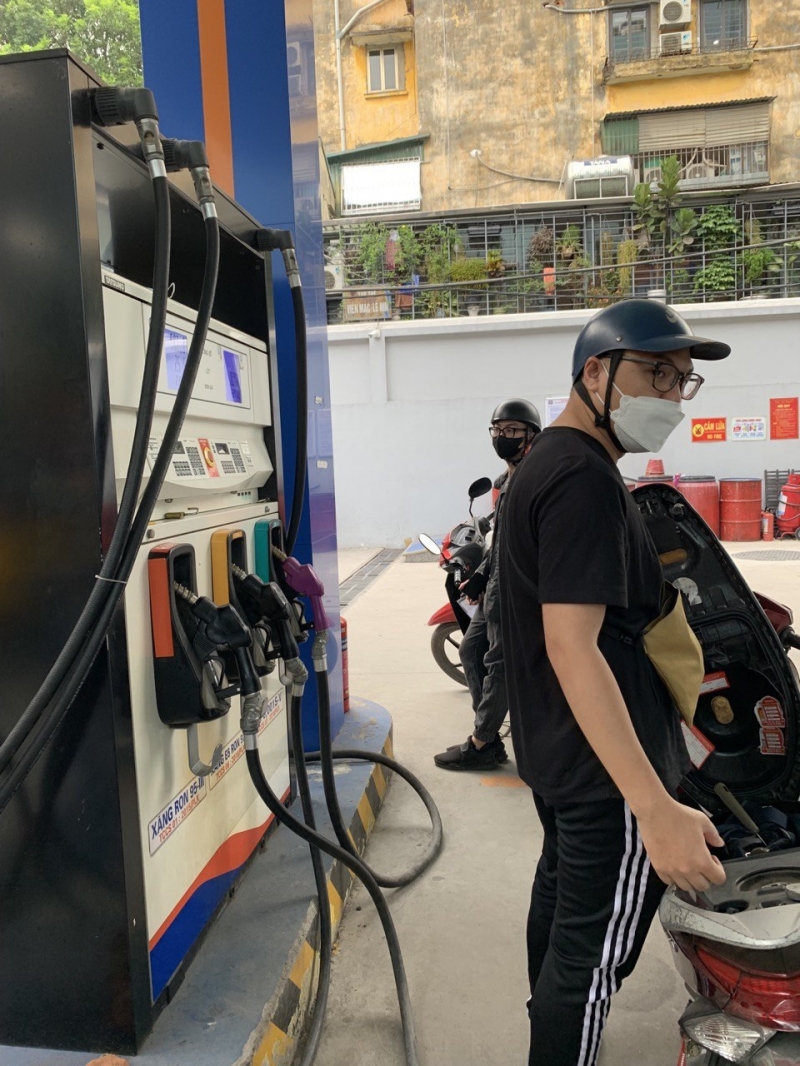 Khách hàng quay lưng đứng đợi nhân viên bán xăng vì chờ lâu - ảnh: Xuân Hưng