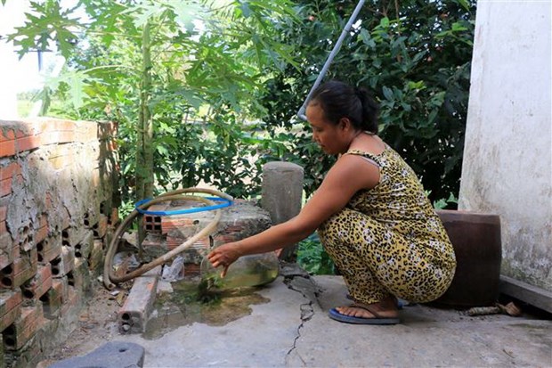 Người dân đổ bỏ những dụng cụ chứa nước không cần thiết để muỗi không có nơi sinh sản. (Ảnh: TTXVN)