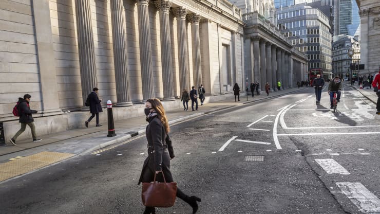 Một người phụ nữ đeo khẩu trang bảo vệ băng qua đường trước Ngân hàng Anh vào giờ cao điểm buổi sáng ở Thành phố London vào ngày 17/3/2020 (Ảnh: CNBC)