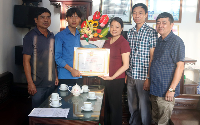 ãnh đạo UBND huyện Hải Hậu trao giấy khen cho em Bùi Hải An (thứ 2, từ trái sang). Ảnh: TTXVN duoinuoc